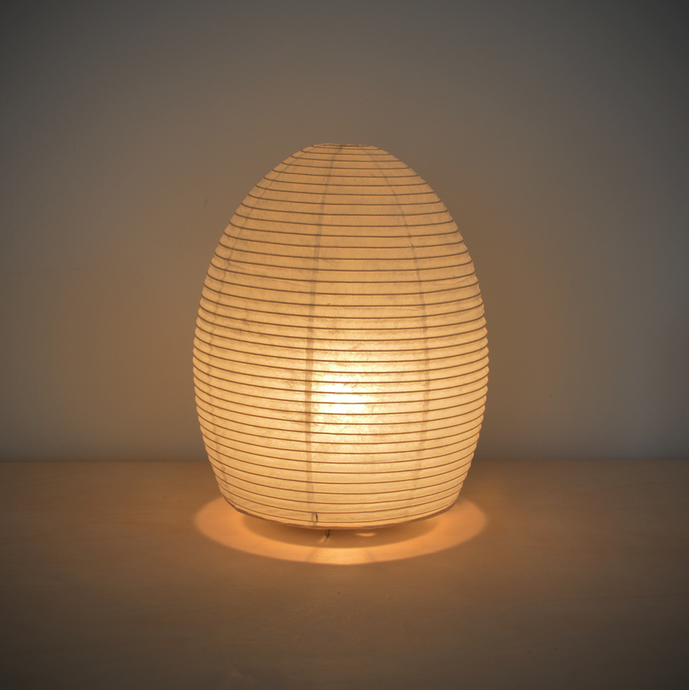 Image of an illuminated egg shaped paper lamp giving off a warm yellowish light.