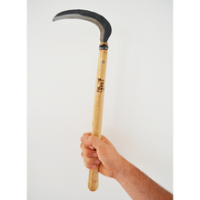 Load image into Gallery viewer, A hand holding up an extra-long wooden handled, hand-held sickle with a rough-hewn blade.
