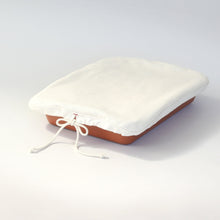 Load image into Gallery viewer, Natural colored cloth with a tied drawstring fitted over a red rectangular serving dish.

