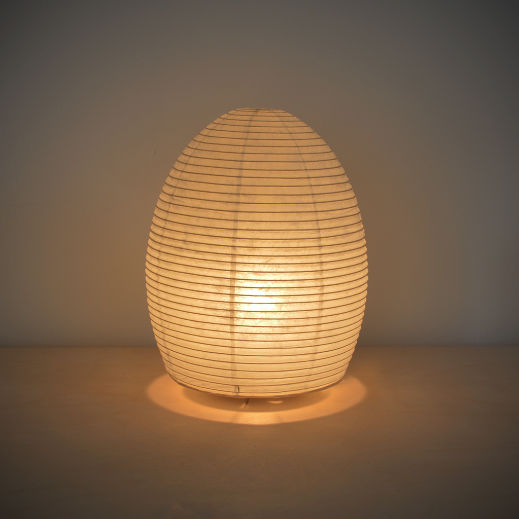 Image of an illuminated egg shaped paper lamp giving off a warm yellowish light.