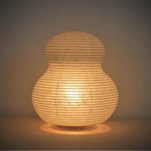 Load image into Gallery viewer, View of an illuminated mushroom shaped paper lantern with a yellowish glow.
