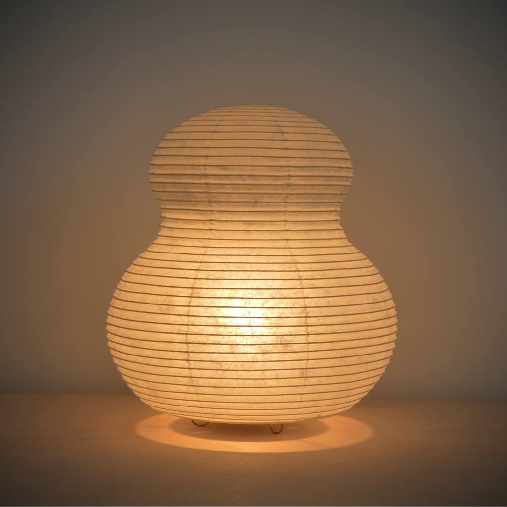 View of an illuminated mushroom shaped paper lantern with a yellowish glow.