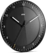 Load image into Gallery viewer, Right 3/4 view of round black clock on white background. The clock face is black and has black hour and minute hands with white tips. The seconds hand is black with a yellow tip. The hours are shown as white numbers.
