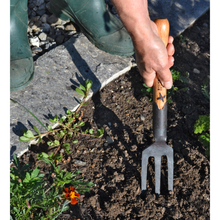 Load image into Gallery viewer, Image of a person using a handheld garden fork to loosen dirt in a garden.
